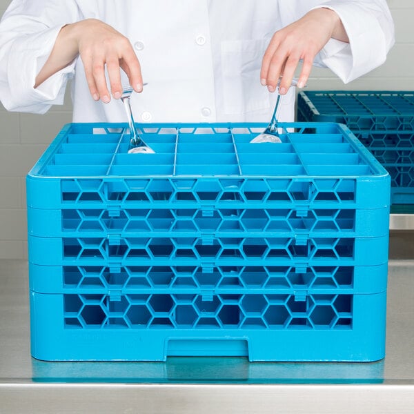 A person holding a blue Carlisle OptiClean glass rack with extenders.