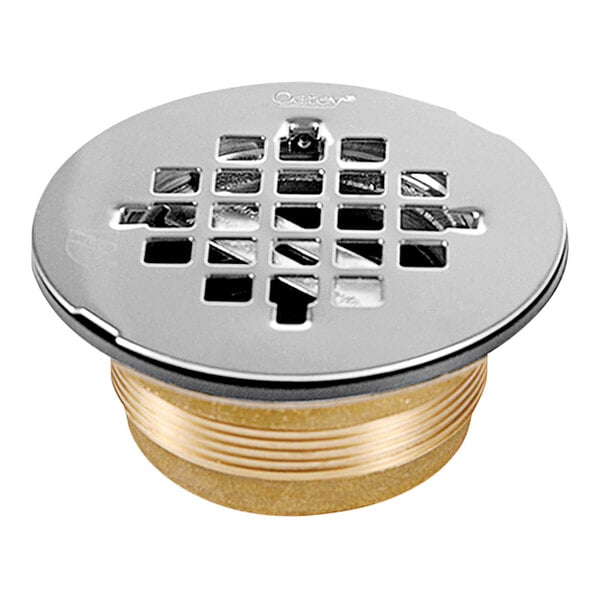 A close-up of an Oatey brass shower drain with a round metal grid.