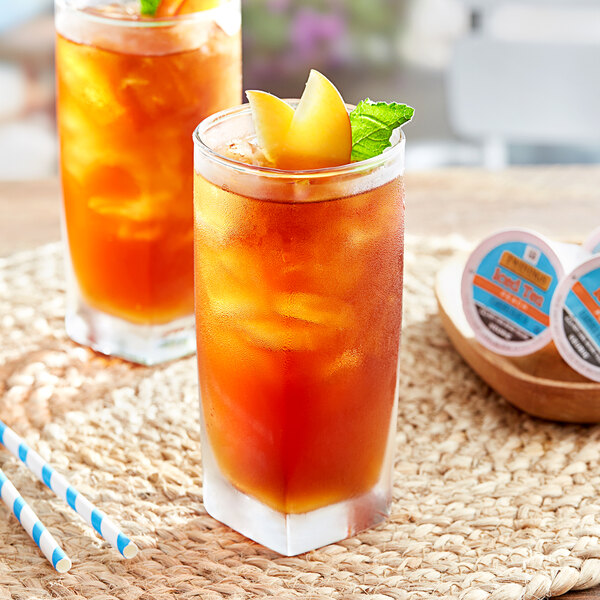 Two glasses of Twinings peach iced tea with lemon and mint.