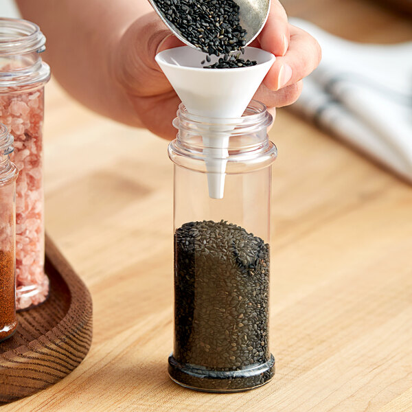 A person pouring black seeds into a plastic container.