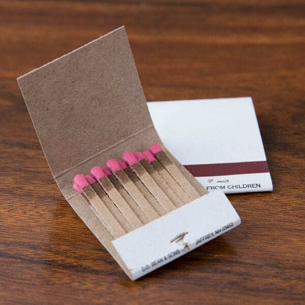 A box of D.D. Bean & Sons Co matchbooks on a table with pink matches inside.