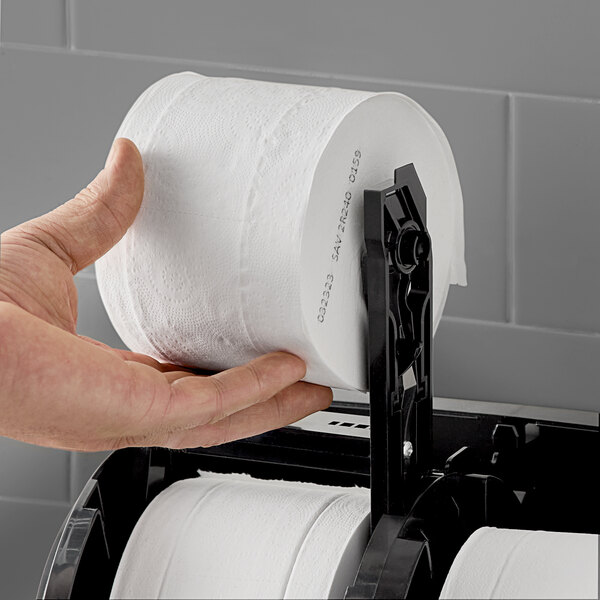A hand holding a roll of Angel Soft Professional Series toilet paper.