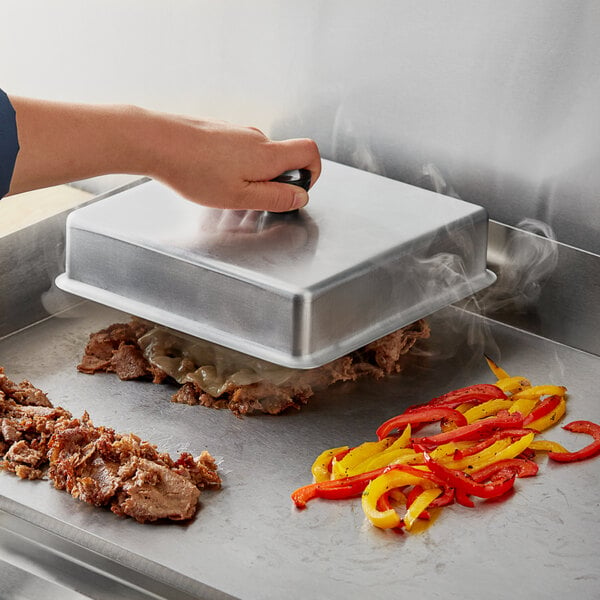 A person using a Choice 8" Square Aluminum Basting Cover to cook meat on a grill.