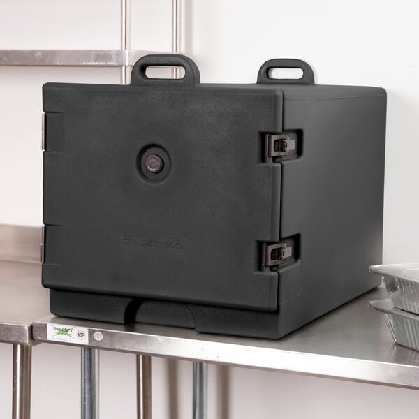 A black Cambro insulated tray carrier on a metal shelf.