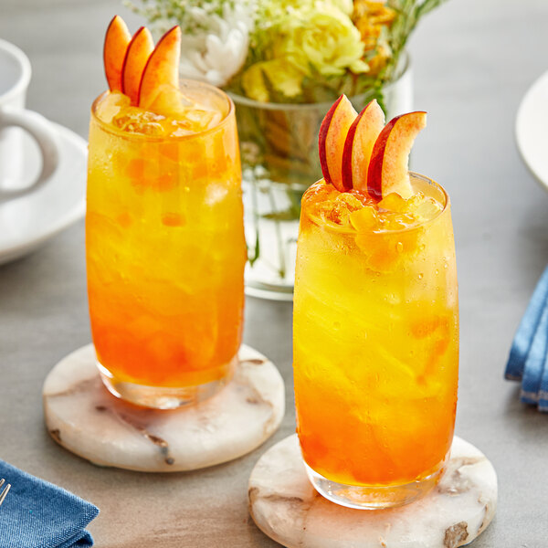 Two glasses of orange and yellow liquid with fruit slices, one with a close up of Fanale Mango Fruit Jam.