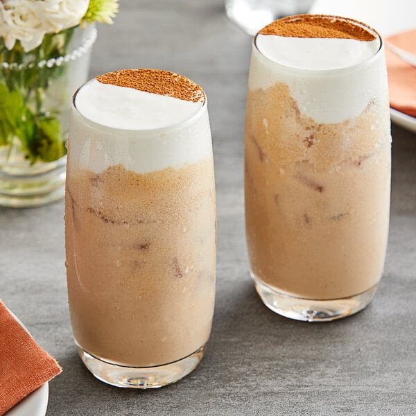 Two glasses of coffee topped with whipped cream and cinnamon made with Fanale Whipping Cheese Powder.