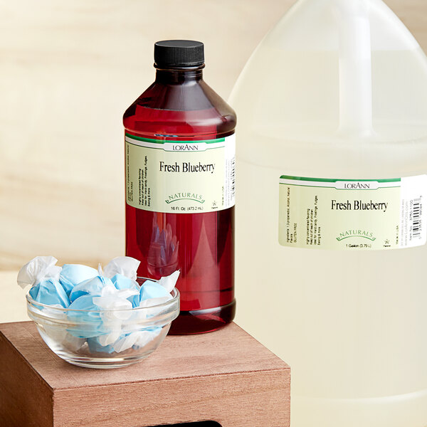 A bottle of LorAnn Oils Fresh Blueberry Natural Flavor next to a bowl of wrapped candy.