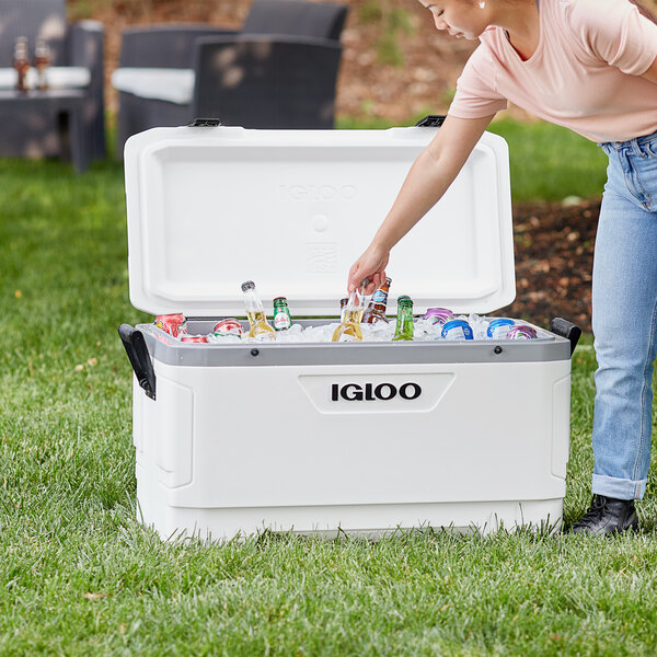 A woman putting bottles into a white Igloo Marine Ultra cooler.