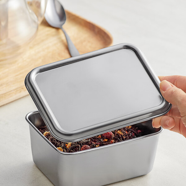 A hand opening a Matfer Bourgeat stainless steel mini container lid.