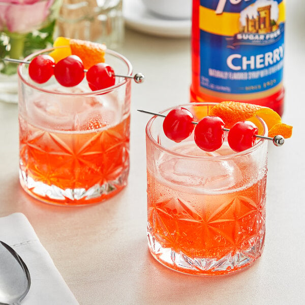 Two glasses of orange liquid with cherries and oranges on them using Torani Sugar-Free Cherry Flavoring Syrup.