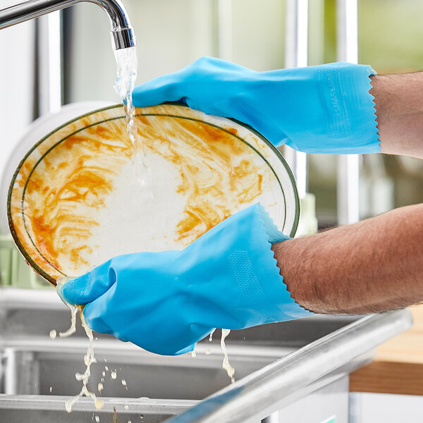 A person wearing Lavex blue latex rubber gloves washing dishes.