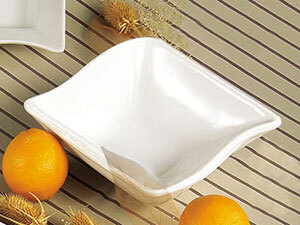 A white square CAC Soho stoneware bowl on a table with oranges.
