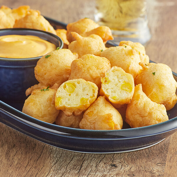 A bowl of fried cheese balls made with Great Lakes Milling Yellow Corn Flour on a table.