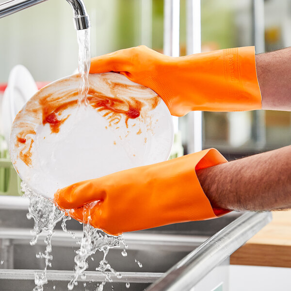 A person wearing an orange Lavex dishwashing glove washing a plate.