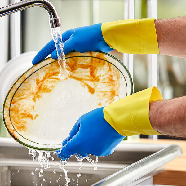 A person wearing blue Lavex neoprene and latex gloves washing a plate.