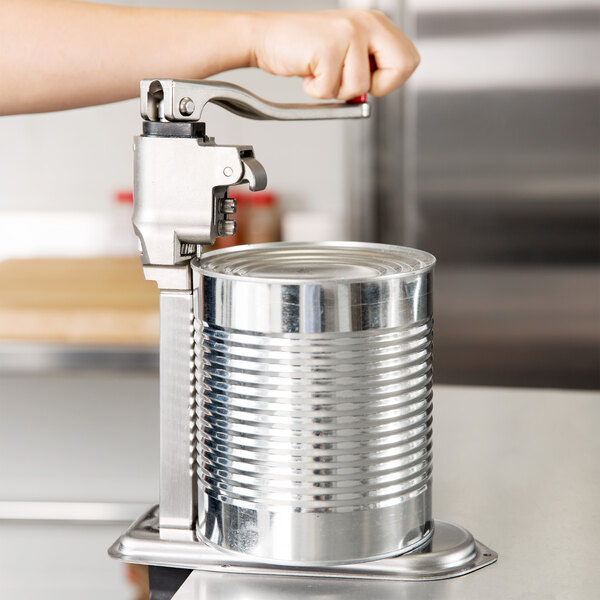A hand using a Vollrath Redco Titan Heavy Duty Can Opener on a can.