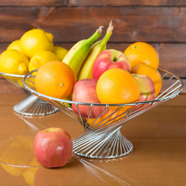 A stainless steel American Metalcraft Whirly Basket filled with fruit on a table.