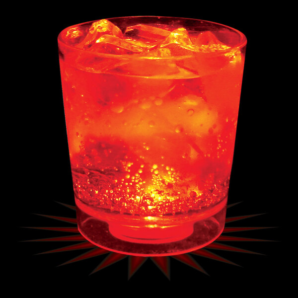 A close-up of a 6 oz. plastic rocks cup with a red drink and ice cubes with a red LED light in the cup.