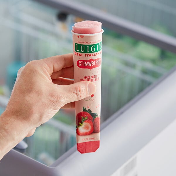 A hand holding a Luigi's Strawberry Italian Ice tube.