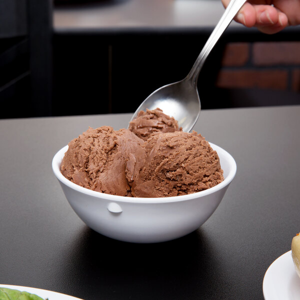 A person holding a spoonful of chocolate ice cream over a white Thunder Group Nustone melamine bowl.