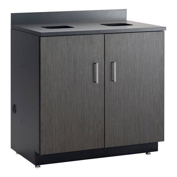 A black cabinet with two doors and a black waste receptacle inside.