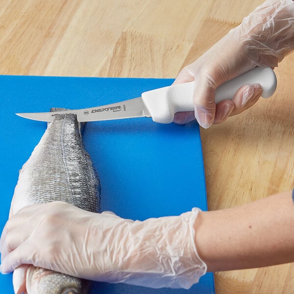 A person in gloves using a Dexter-Russell curved boning knife to cut a fish.