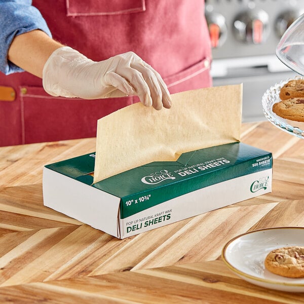A person wearing a glove using EcoChoice deli wrap to put a cookie in a box.