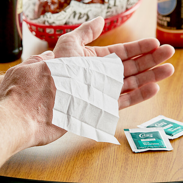 A hand holding a lemon-scented moist towelette.