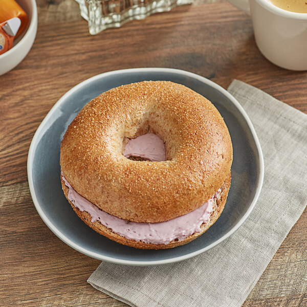 An Original Bagel New York Style Honey Wheat bagel with cream cheese and jelly on a plate.