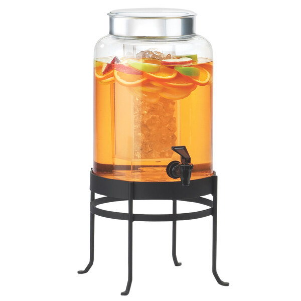 A Cal-Mil black glass beverage dispenser with an ice chamber on a metal stand filled with liquid and fruit.