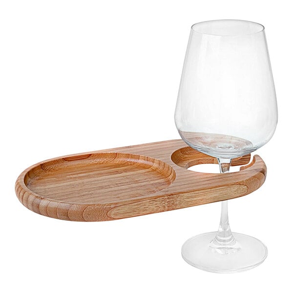 A Franmara oval bamboo party plate with a built-in stemware holder holding a wine glass.