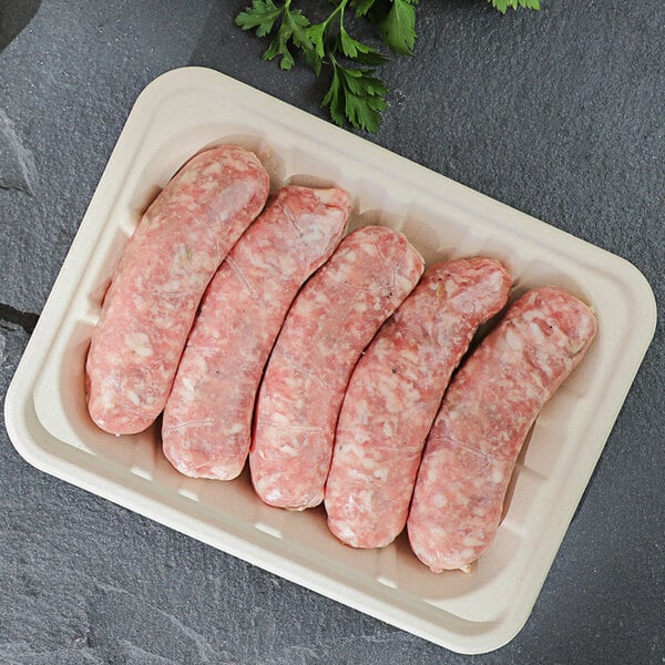 A World Centric compostable fiber meat tray with raw sausages on it.
