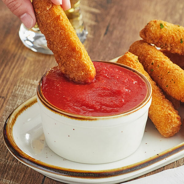 A hand dipping a fried stick into a bowl of Stanislaus Full Red California tomato sauce.