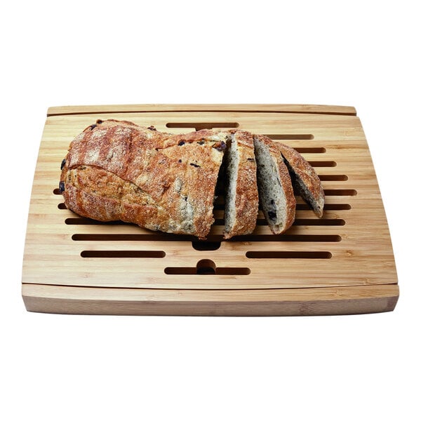 A loaf of bread on a Franmara bamboo cutting board with crumb tray.