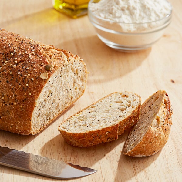 A loaf of bread with a knife and a bowl of Caputo 00 Saccorosso flour.