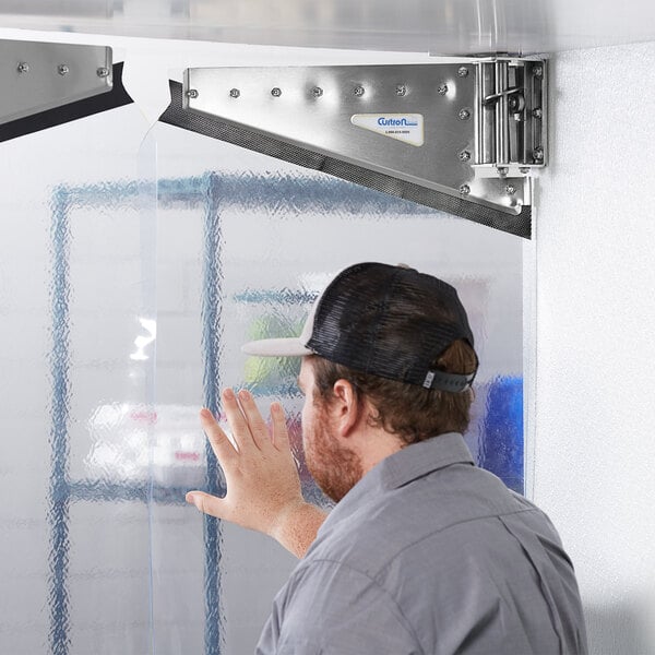 A man using his hand to open a Curtron Polar-Pro swinging strip door.