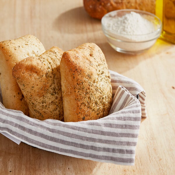 A basket of bread on a table with a bowl of olive oil.