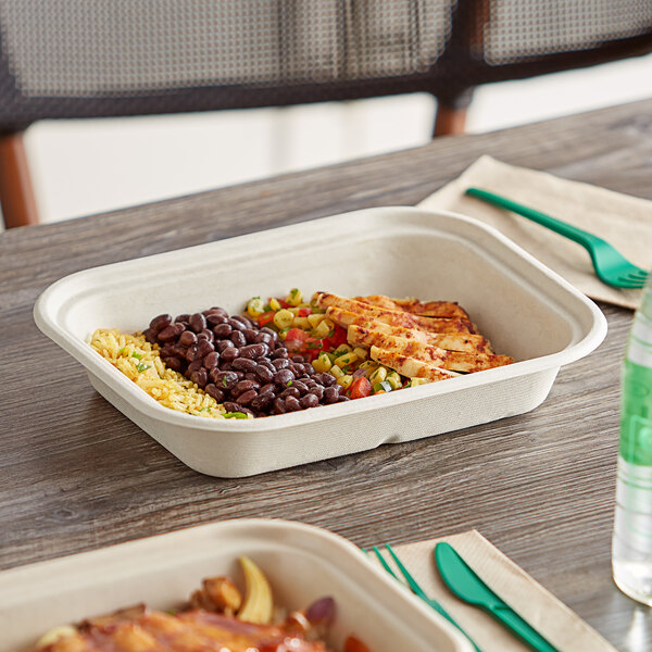 A white World Centric compostable container with food inside on a table.