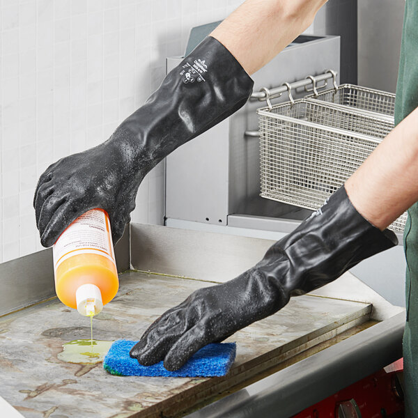 A person wearing a black Showa neoprene glove cleaning a surface.