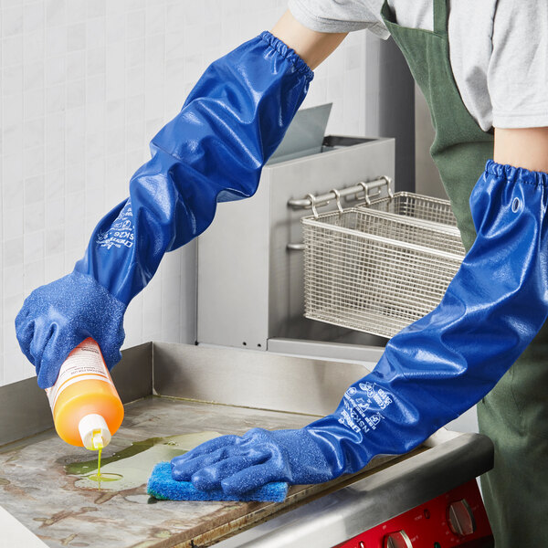 A person wearing Showa blue cotton-lined nitrile gloves cleaning a surface.