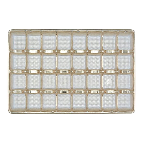 A close-up of a gold 32-cavity candy tray with many white square holes.