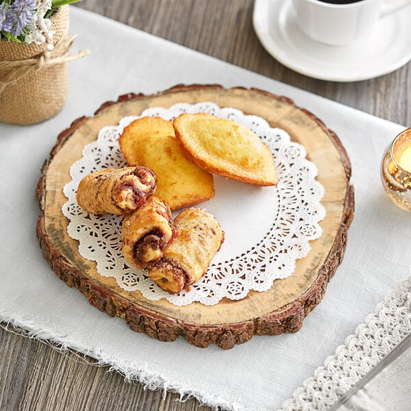 A wood surface with a plate of Normandy lace doilies with pastries and a cup of coffee.