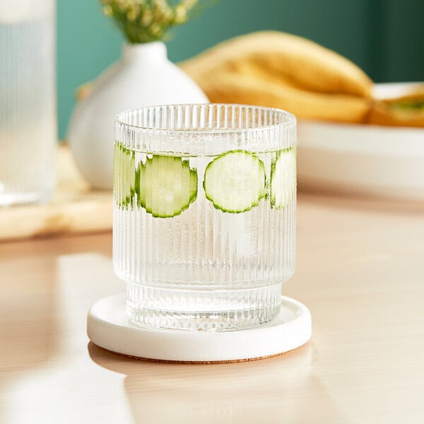 A glass of water with cucumber slices in an Acopa Lore Rocks glass.