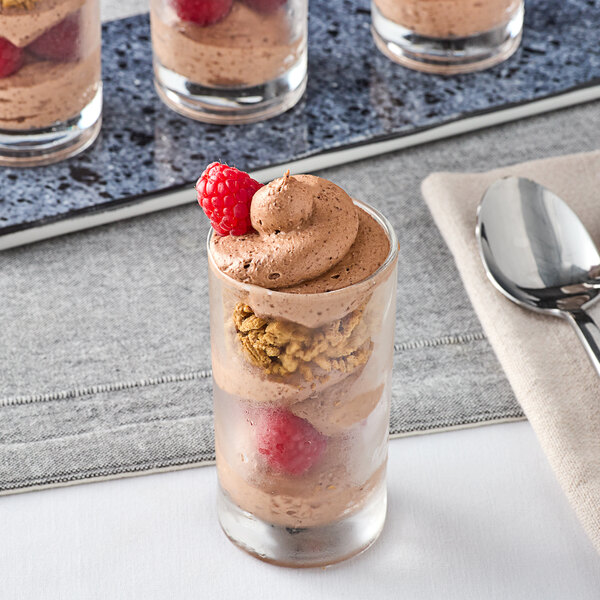 A glass with chocolate mousse topped with a raspberry.