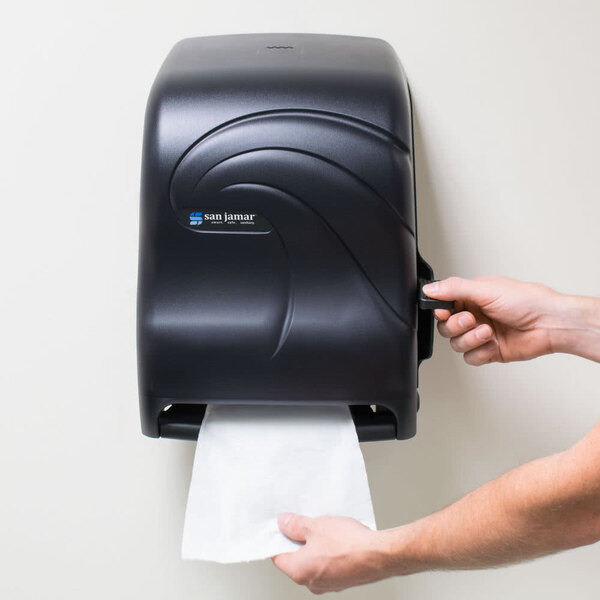 A person using a San Jamar black pearl paper towel dispenser to get a paper towel.