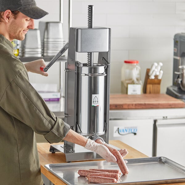 A man using a Tre Spade stainless steel sausage stuffer on a countertop to make sausages.