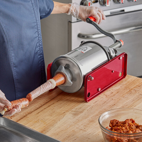 A person using a Tre Spade manual sausage stuffer to make sausages.