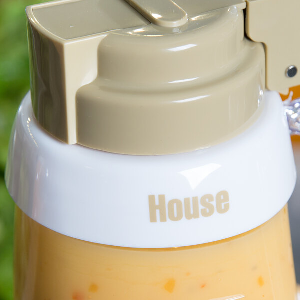 A Tablecraft white plastic dispenser collar with beige lettering on a brown liquid container.