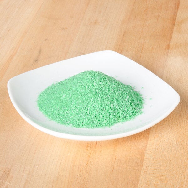 A small white plate with green salt on it.