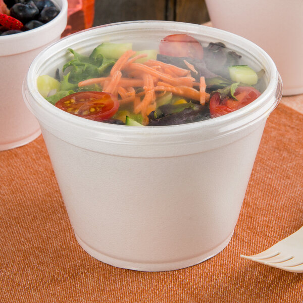 A close-up of a clear plastic container with a salad inside.